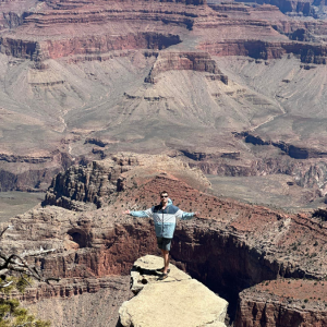 Brendan, arms outstretched at the Grand Canyon's edge.