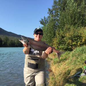 Jackie, General Manager, with a fish by a river.